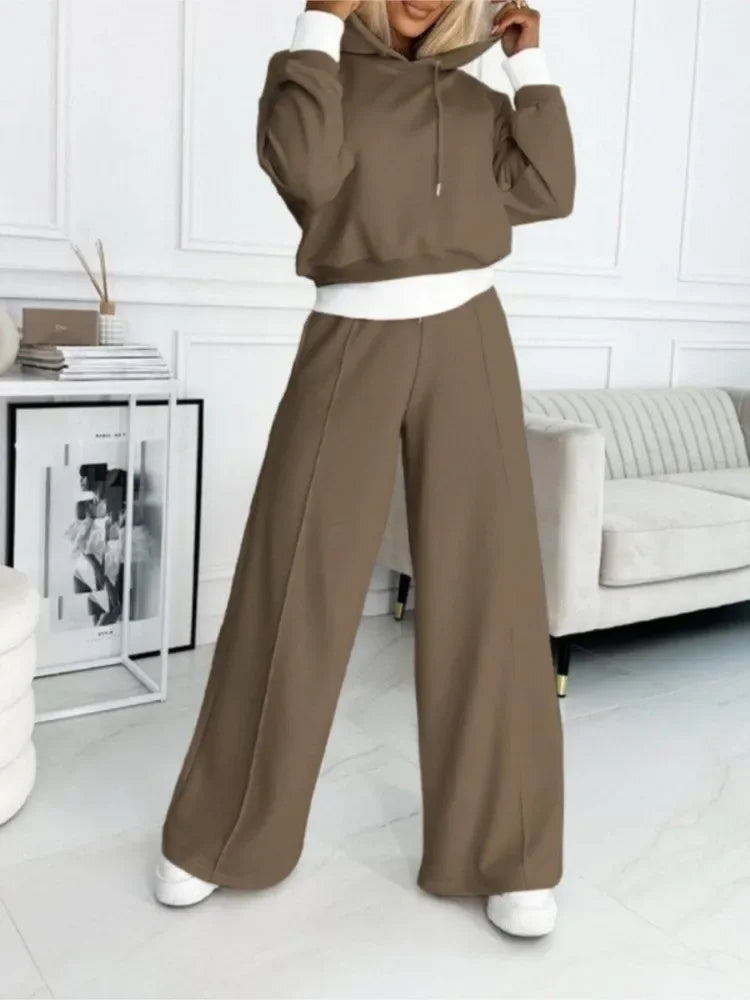 Model in a brown hoodie and wide-leg pants with white cuffs and waistband, hands holding the hood 17