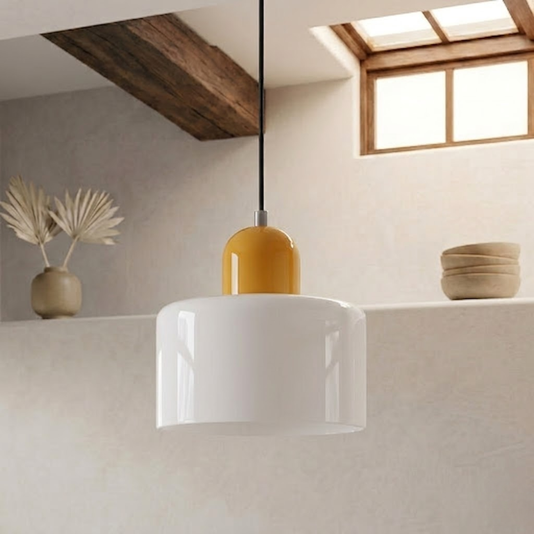 Glossy white drum shade with a mustard yellow dome cap hangs on a black cord in a plaster-walled room. 23