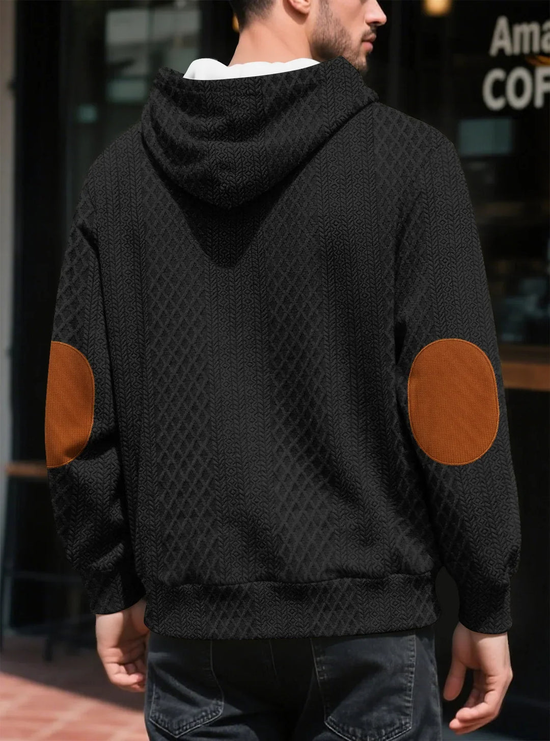 Back view of a man in a black textured hoodie showing large brown elbow patches and ribbed hem 17