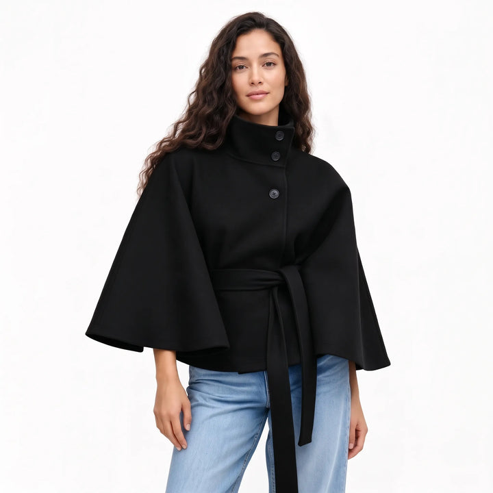 Studio shot of a model in the black cape jacket, wide flared sleeves and belt tied at the waist 17