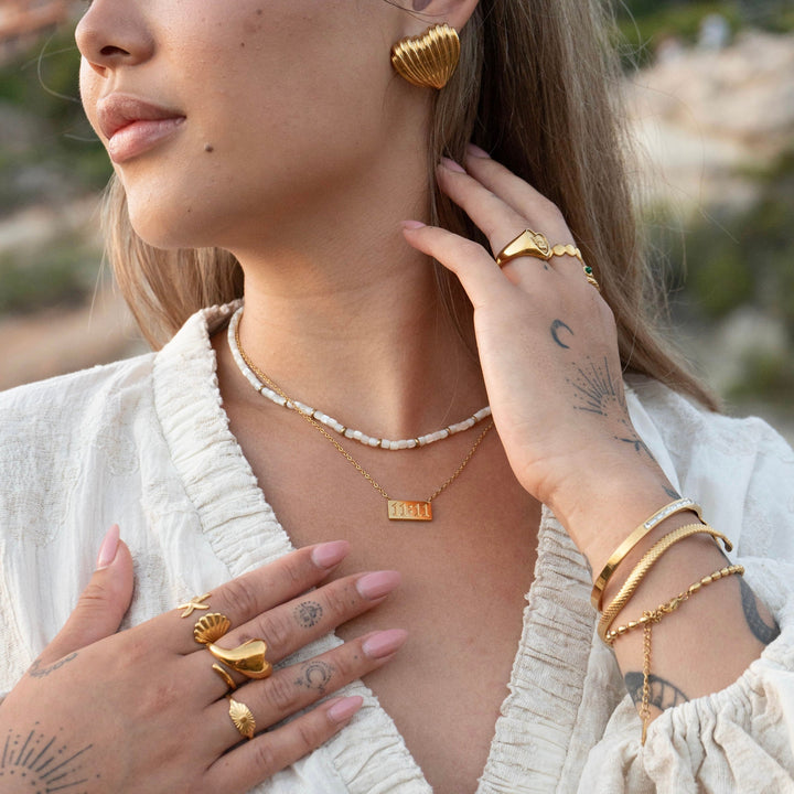 Lucky Elevens Necklace worn with layered jewelry and a white bead necklace.