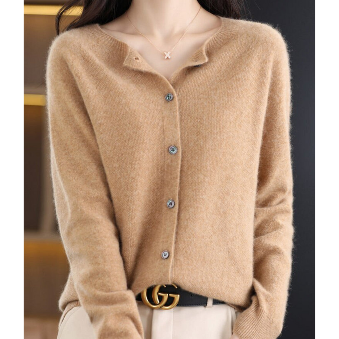 Woman wearing a camel tan fuzzy knit cardigan with button front and X pendant necklace, styled with cream trousers and a black belt. 11