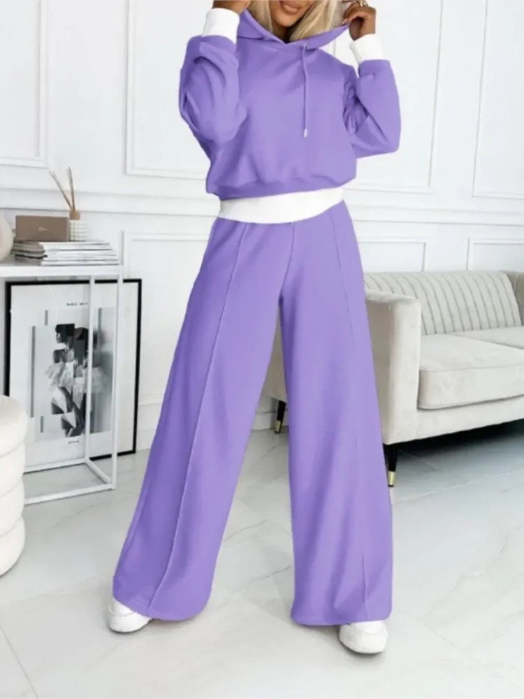 Model in a lavender hoodie and wide-leg pants, hands at the hood, standing in a bright living room 18