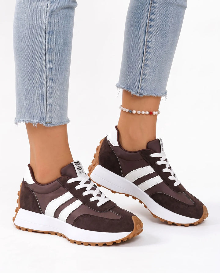 Dark brown trainers with white stripes and a gum sole, worn with light jeans and a pearl anklet 18