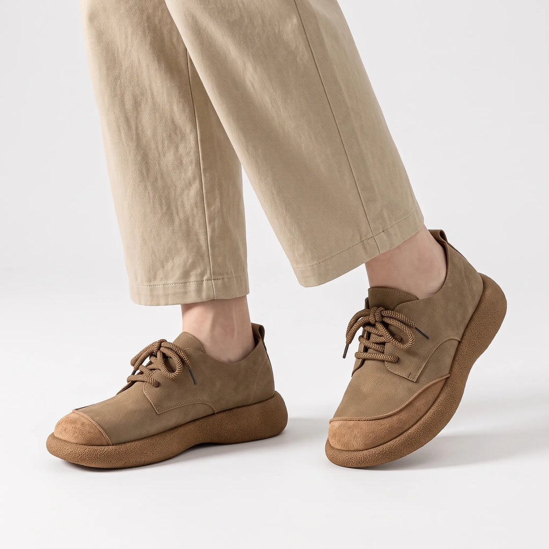 Khaki lace-up shoes with chunky soles worn with beige trousers, one foot tilted 19