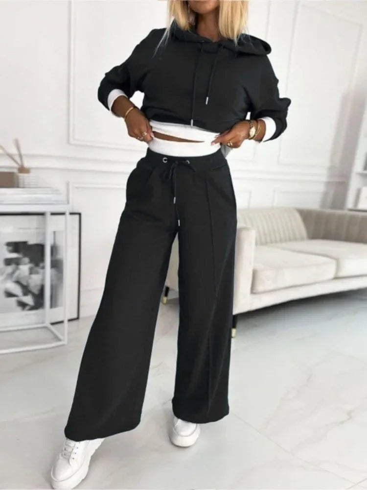 Model in a black hoodie and drawstring wide-leg pants, hands at the hem showing white inner layer 19