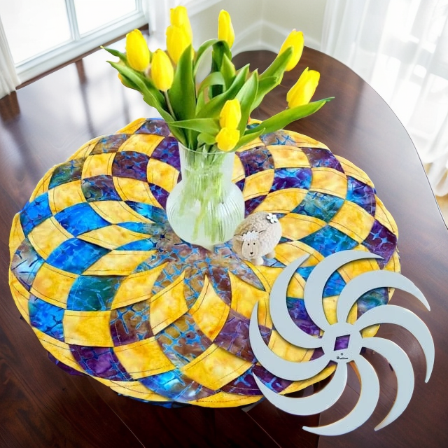 Round placemat in yellow, blue and purple under a vase of yellow tulips beside a white spiral template.