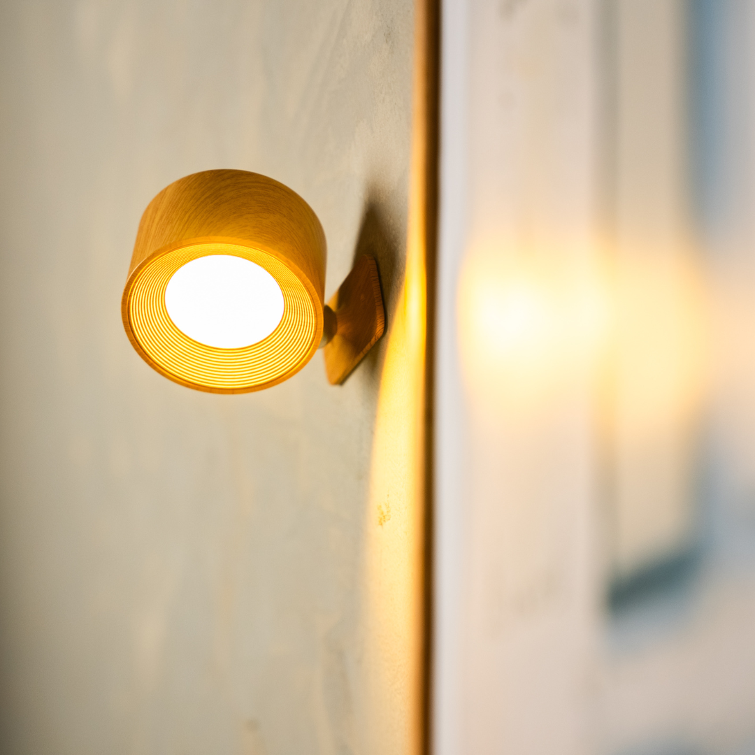 Close-up of the black wireless LED wall light showing the glowing round LED and ribbed ring.