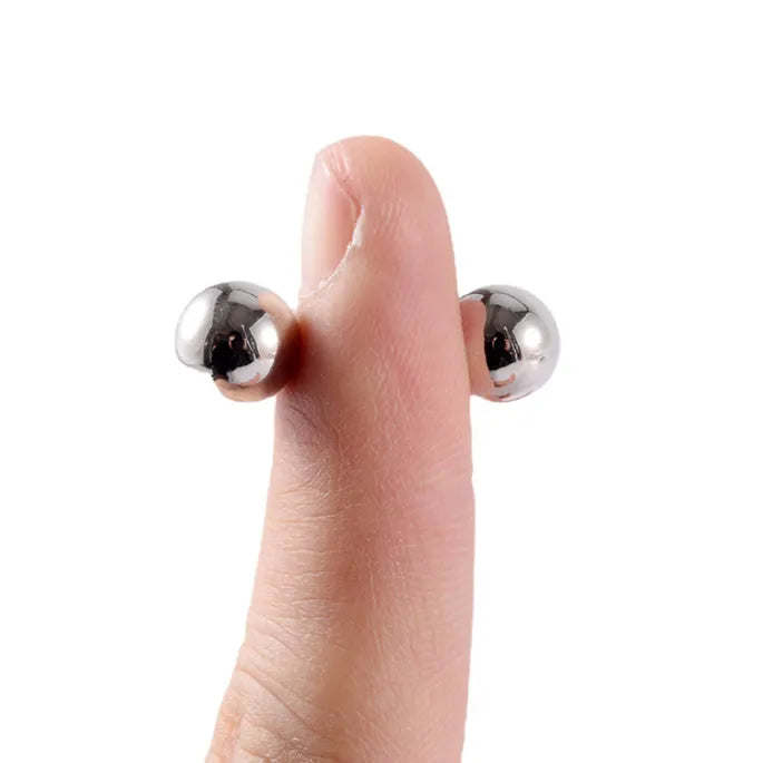 Fingertip with one silver magnetic ball on each side, showing how the two halves grip through skin.