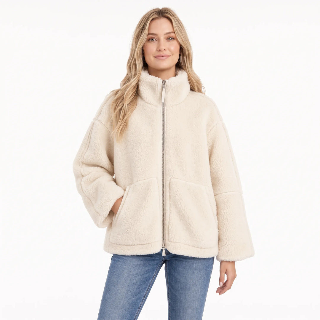 Model in a cream fleece zip coat with stand collar and patch pockets, worn with blue jeans 1