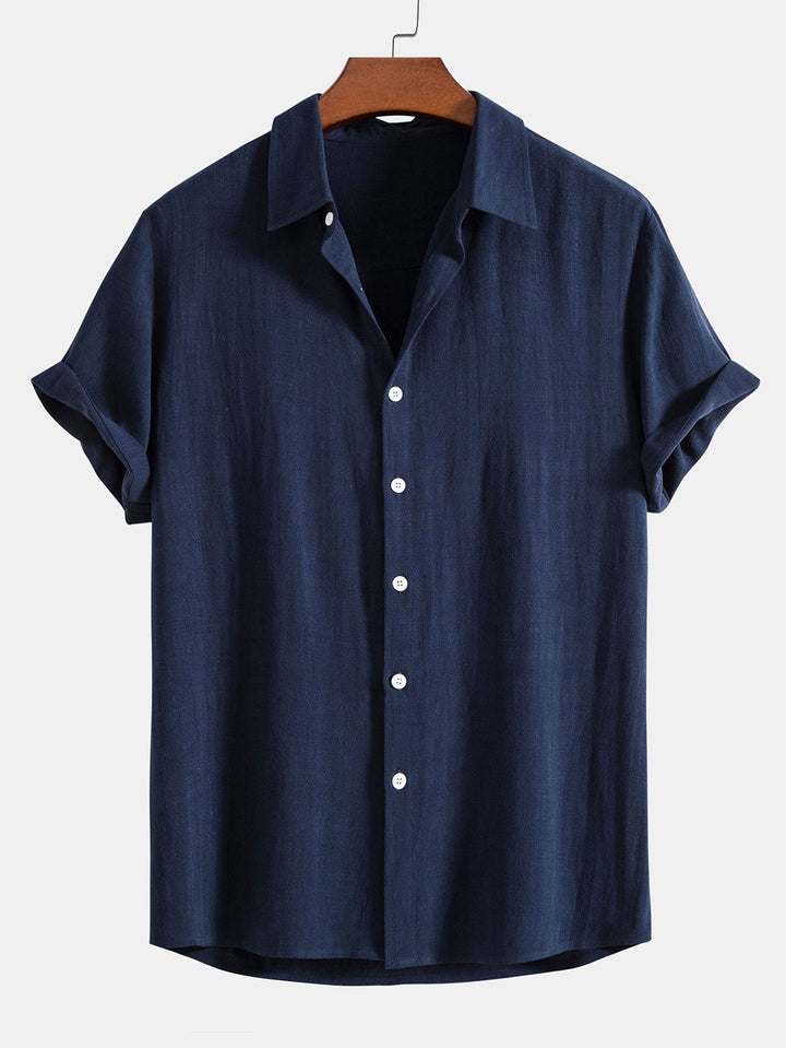Navy blue short sleeve shirt on a wooden hanger, front view with white buttons and cuffed sleeves.