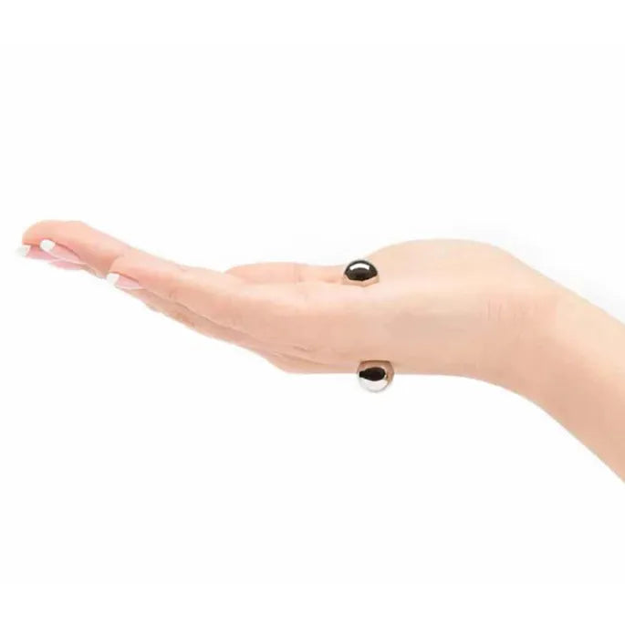Open palm viewed from the side with two silver magnetic balls holding on opposite sides of the hand.