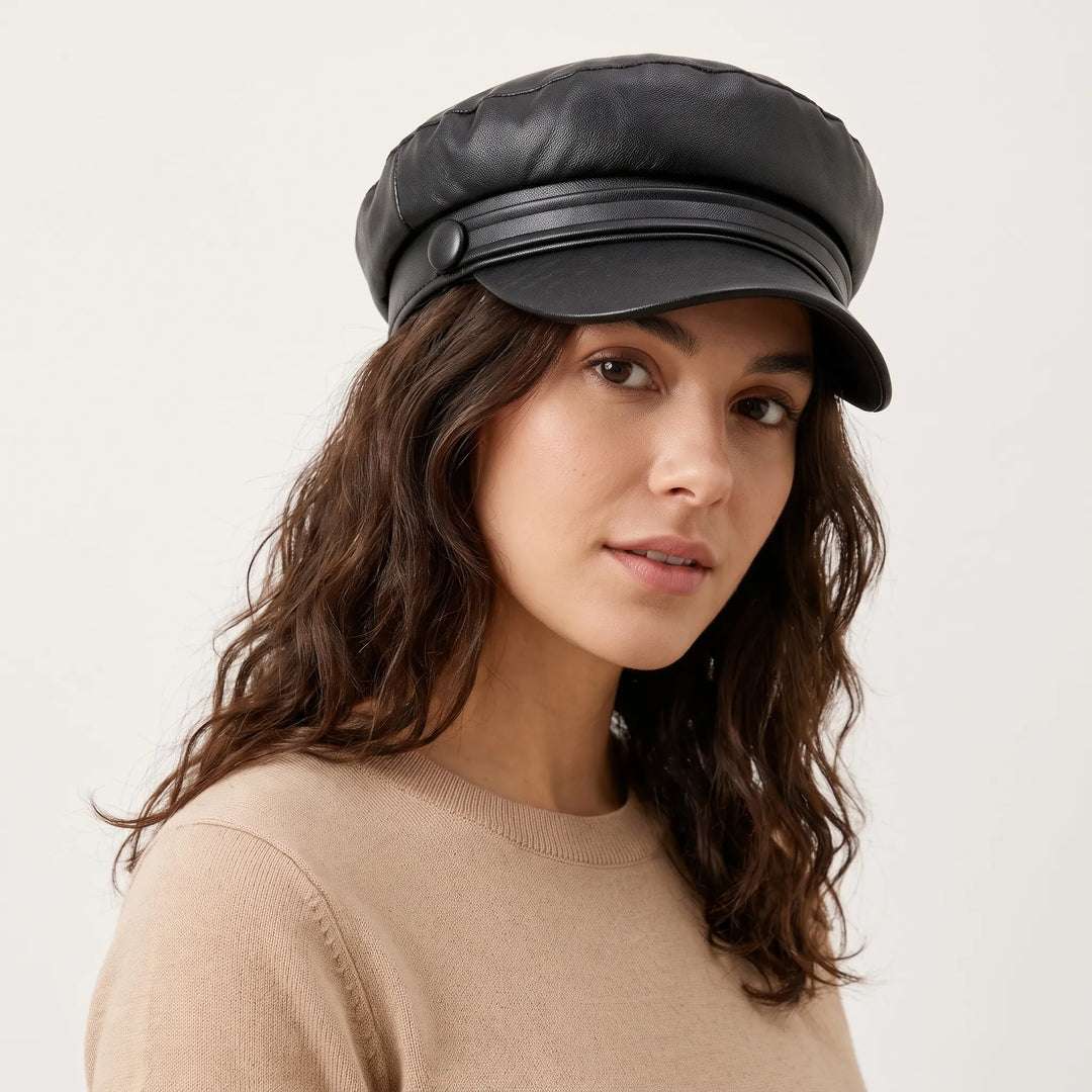 Woman with wavy brown hair wearing the black leather-look cap with button strap, turned slightly to the side 1
