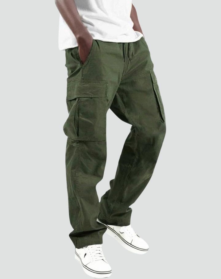 Model wearing olive green cargo pants with a white tee and white sneakers, hand in pocket, side view on gray. 1