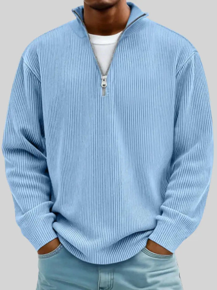 Man wearing the ribbed quarter-zip sweater in light sky blue over a white tee, hands in jeans pockets.