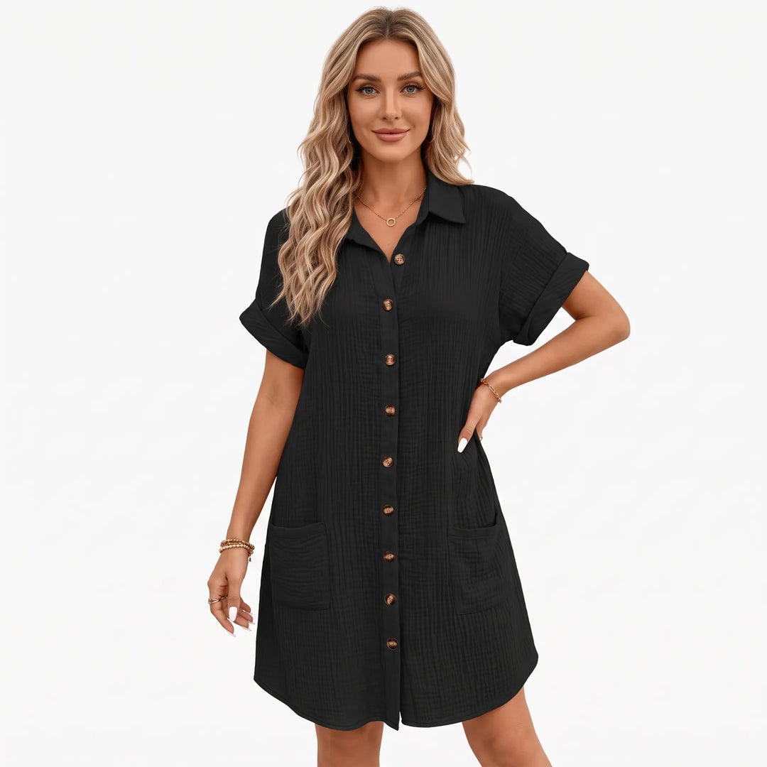 Black crinkled button-front shirt dress worn by a model, one hand on hip, studio front view 1