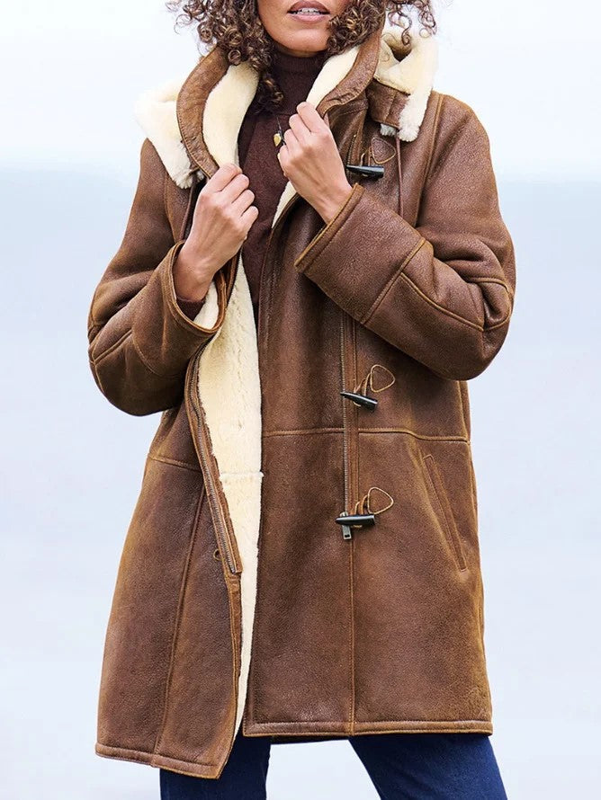 Woman wearing the brown coat open at the front, holding the cream fleece collar, with toggle fastenings and a front zipper visible. 1