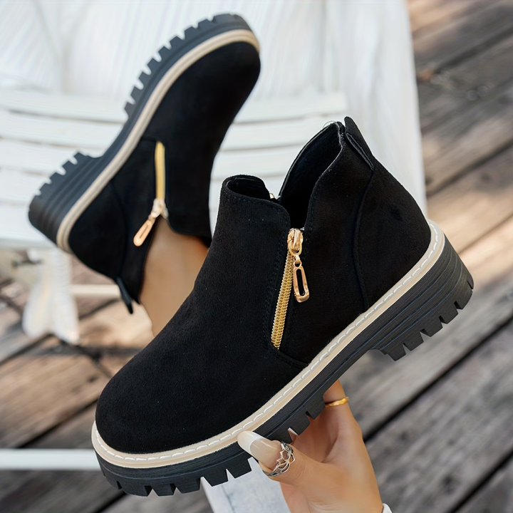 Black suede-look ankle boots with gold side zippers and chunky lug soles.