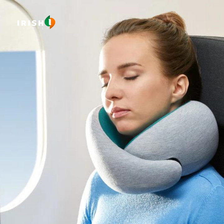 Gray front-support travel neck pillow with teal lining, worn under the chin beside an airplane window.