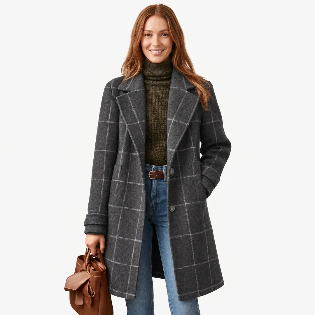 Smiling woman in a charcoal gray window-pane coat with an olive turtleneck, jeans and brown tote 1