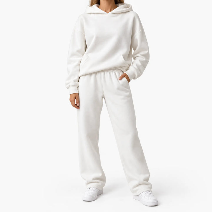 Model in the white hooded sweatshirt and straight-leg sweatpants set, one hand in pocket, with white sneakers 1