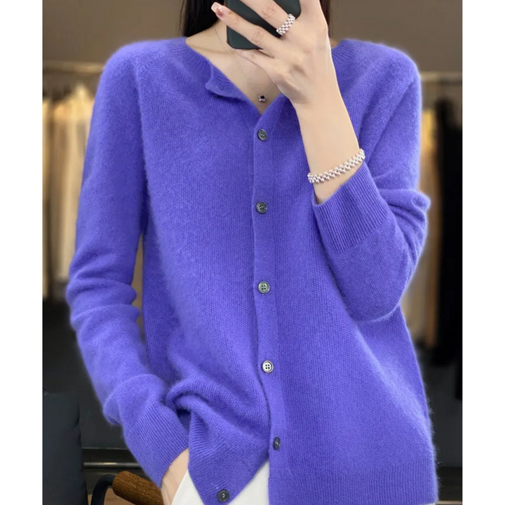 Woman in a vivid violet-blue knit cardigan with dark buttons, taking a mirror selfie with her phone in a boutique setting. 3