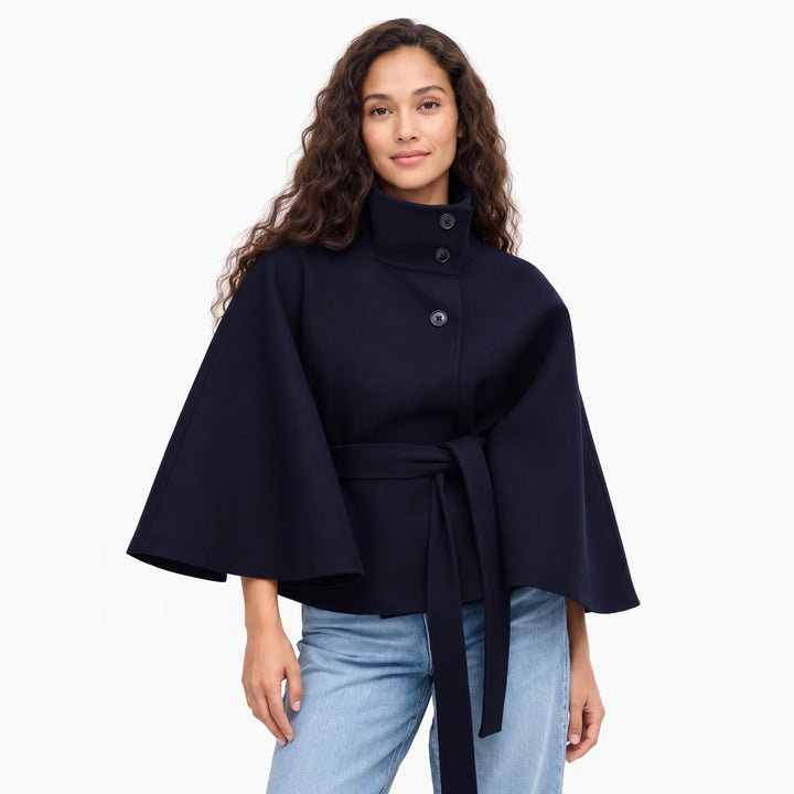 Model with long wavy hair wears the navy cape jacket with jeans, belt tied at the waist 1