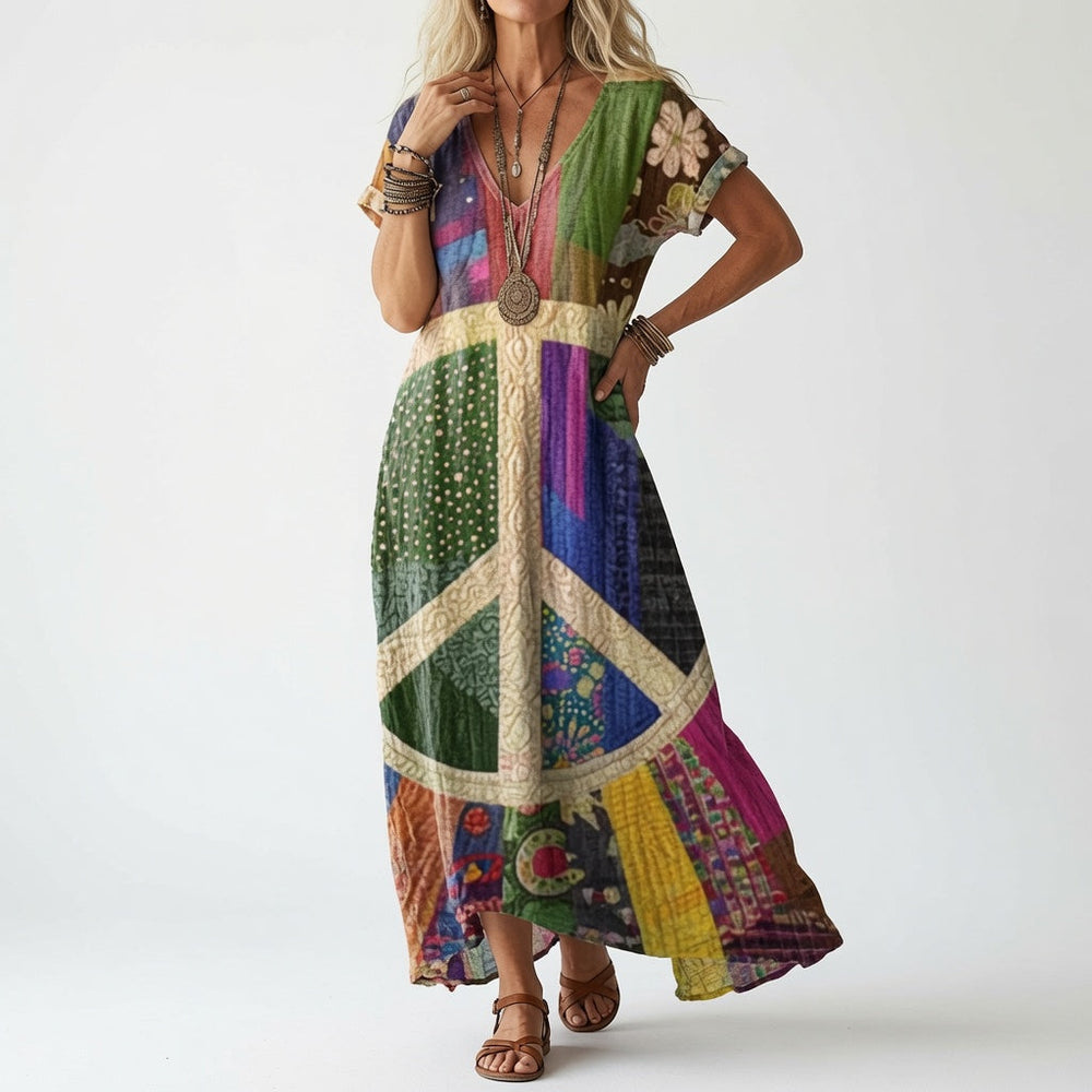 Woman in a colorful patchwork V-neck dress with a large cream peace symbol on the front, worn with brown leather sandals.