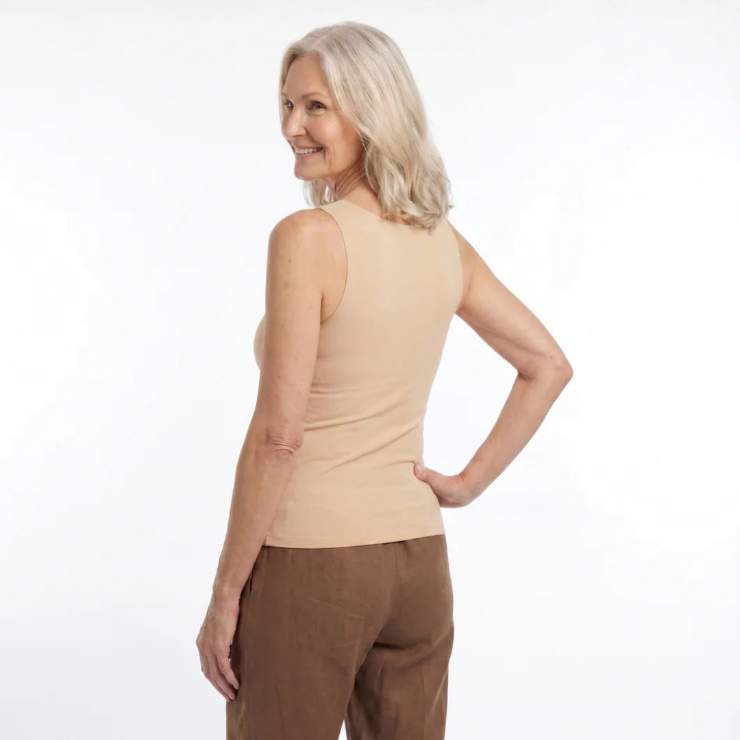 Back view of a woman glancing over her shoulder, wearing the beige tank with a smooth, plain back and brown linen pants. 6