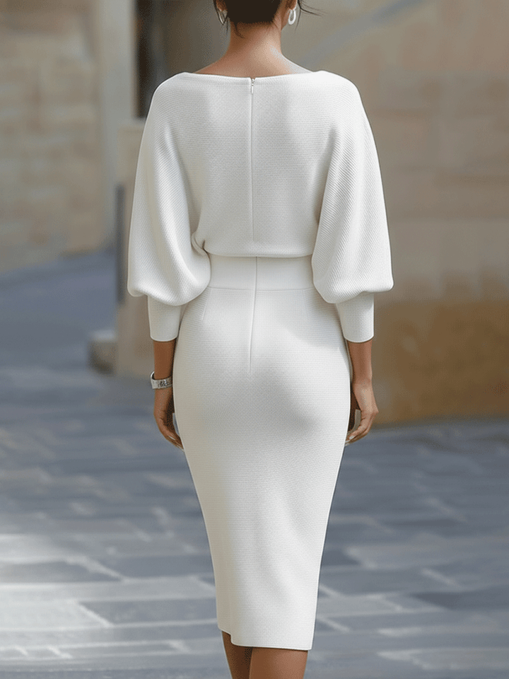 Back view of the white dress showing the center zipper, wide batwing sleeves and slim skirt 7