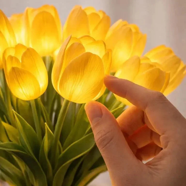 Detail of a hand touching a glowing yellow LED flower bloom with warm light.