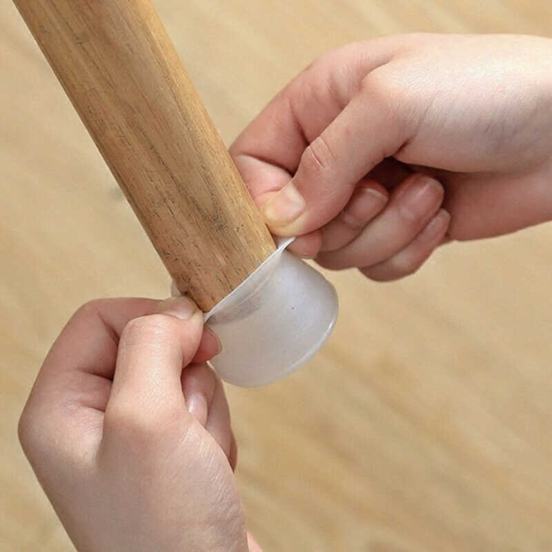 Hands stretching a translucent silicone cap over the bottom of a round wooden furniture leg 1