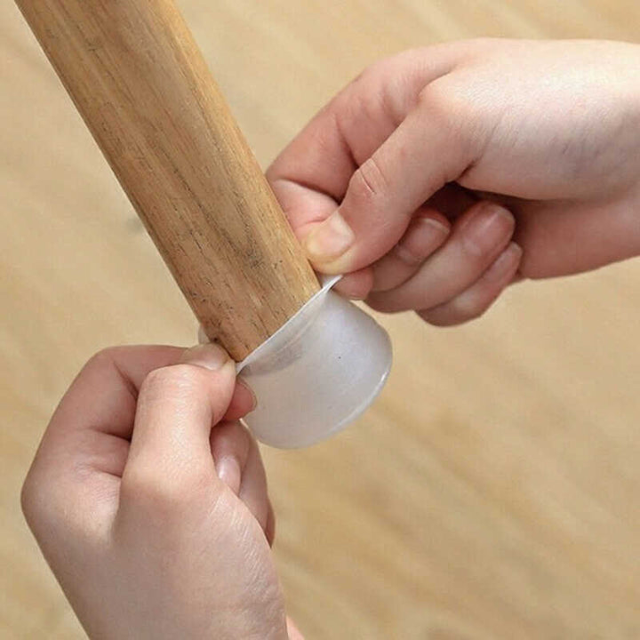 Hands stretching a translucent silicone cap over the bottom of a round wooden furniture leg 1