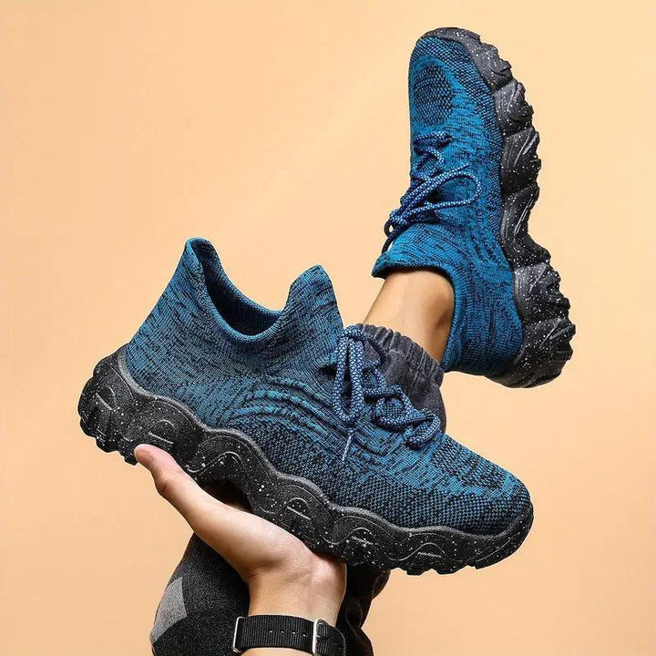 Blue knit sneaker held up in one hand beside a worn pair, showing the lacing and black speckled chunky sole. 31