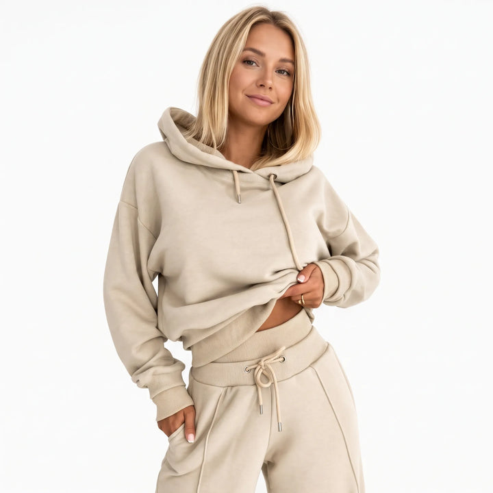 Model in a beige hooded sweatshirt and matching wide-leg pants, one hand in pocket, front view 21