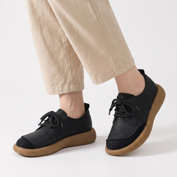 Model wearing black lace-up shoes with suede toe caps and thick tan soles, with beige trousers 21