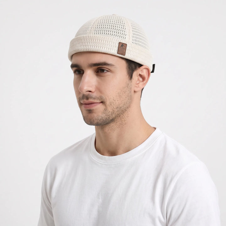 Man in a white tee wears the cream open-weave brimless cap, seen from the front-left 22