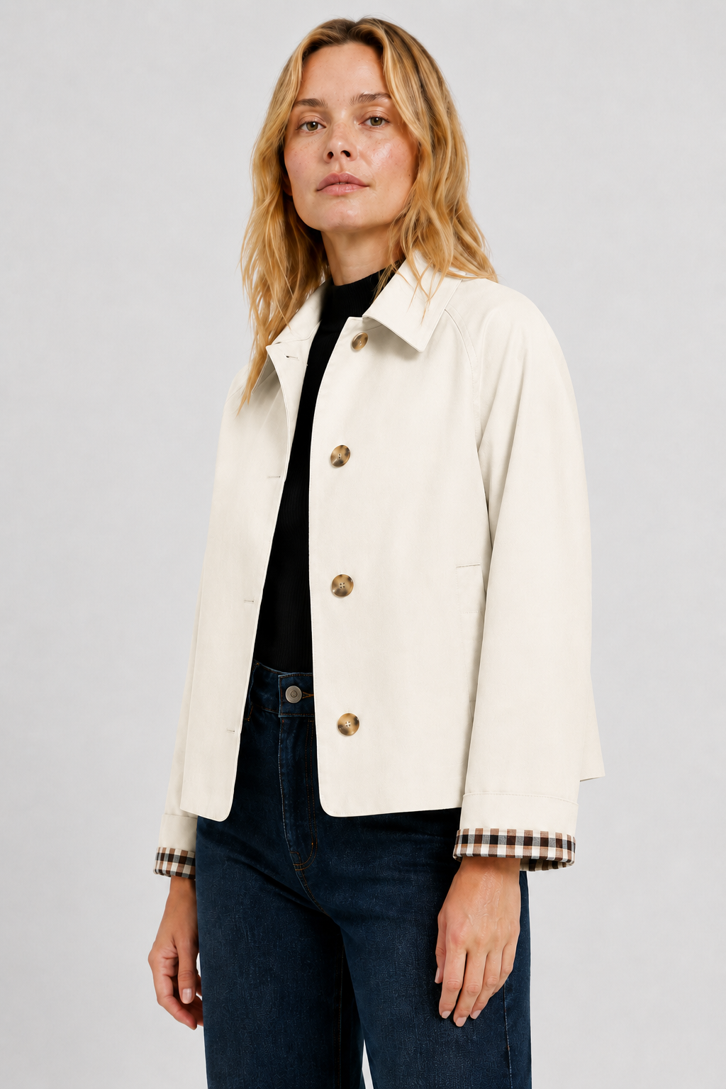 Three-quarter view of the cream jacket worn open over a black top and dark jeans, with checked lining on the turned-up cuffs. 22