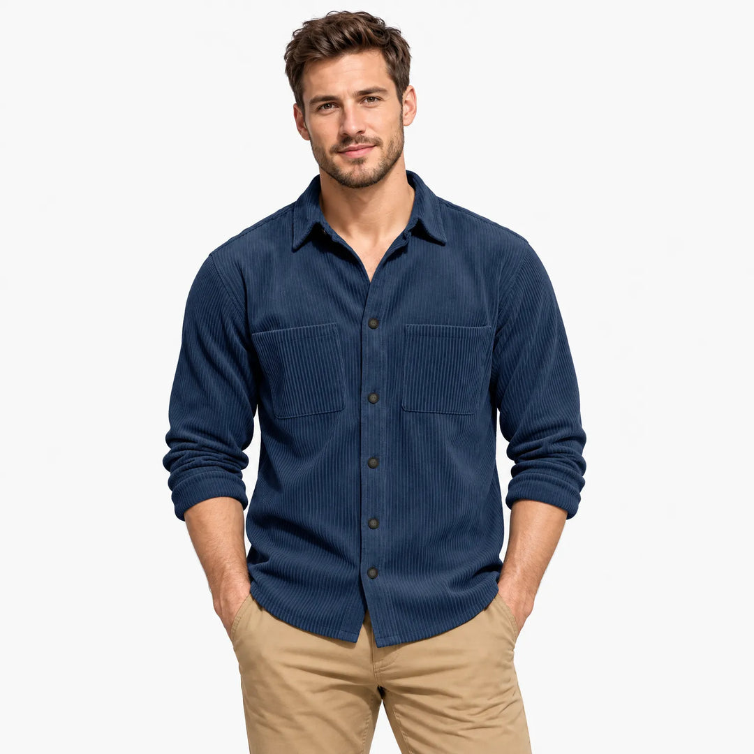 Man in a navy blue corduroy shirt with two chest pockets and rolled sleeves, hands in pockets 23