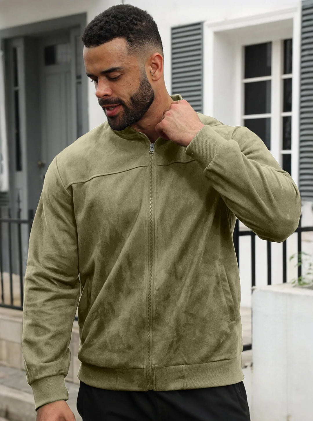 Man wearing olive green suede-look zip-up jacket outdoors, front view, hand raised to his collar 23