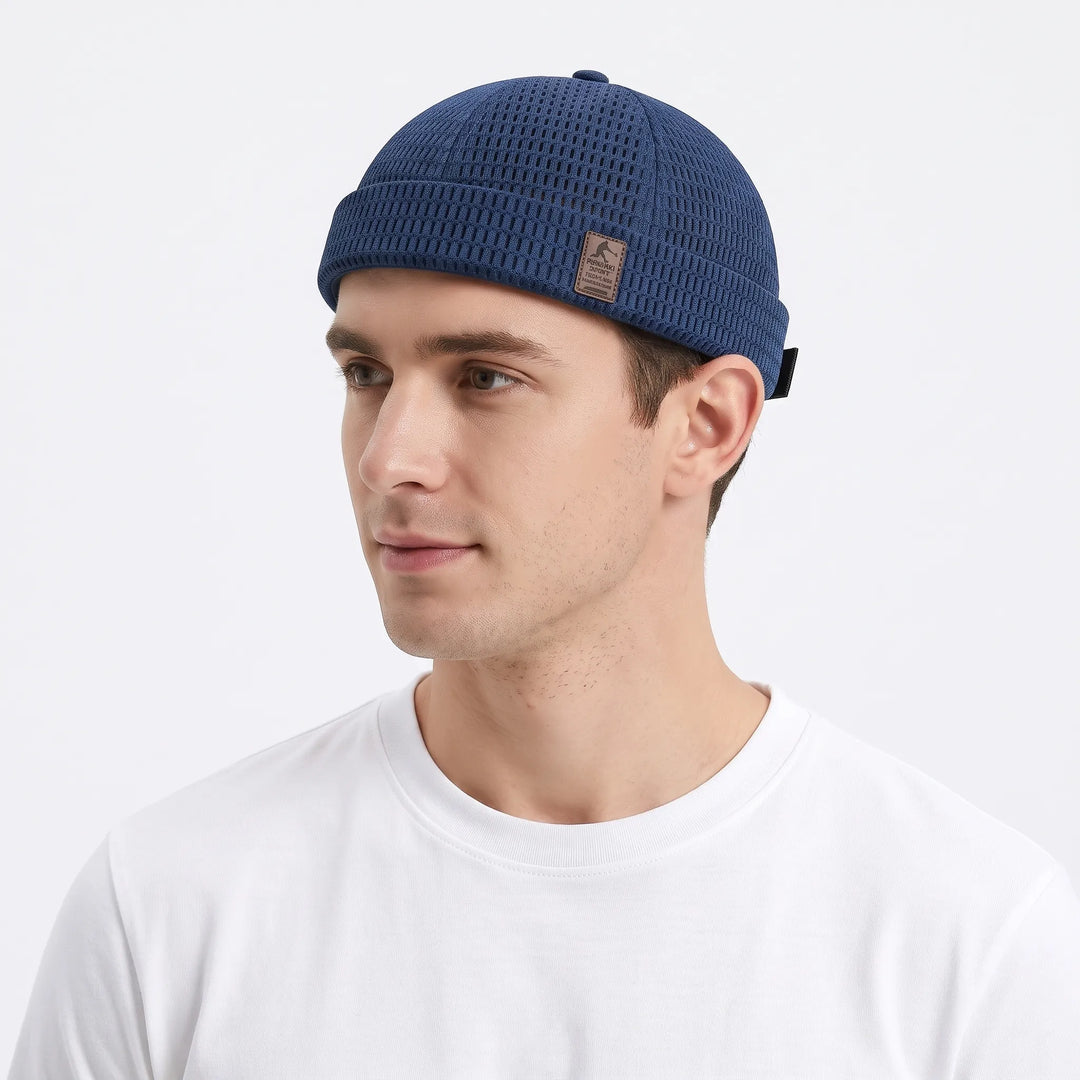 Man in a white tee wears the navy blue open-weave brimless cap, turned slightly to the left 25