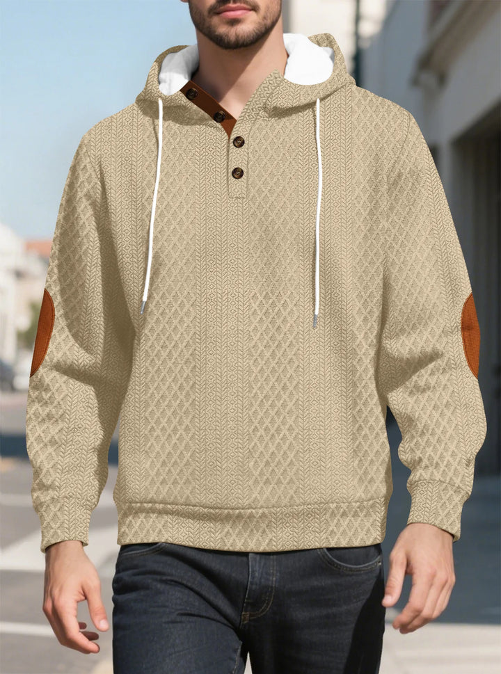 Man walking outdoors in the beige diamond-textured hoodie, front view with brown elbow patches 26