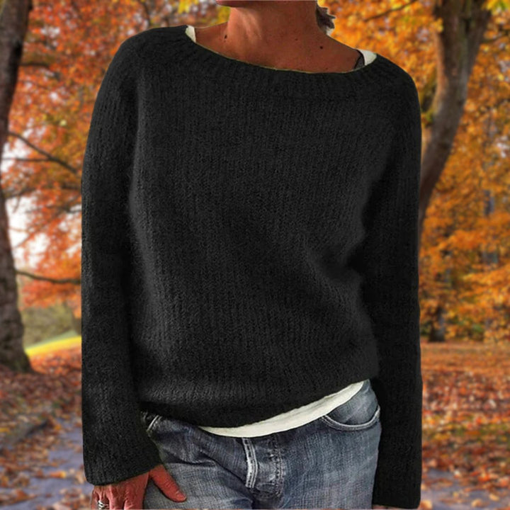Black knit sweater with a round neck, worn over a white tee and jeans in an autumn park 2