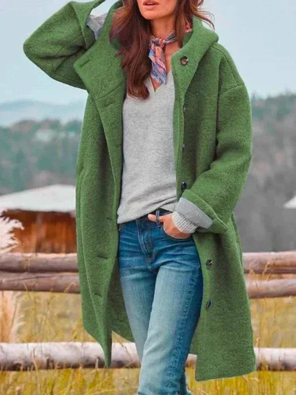 Women's green hooded coat open, shown in another view by a wooden fence.