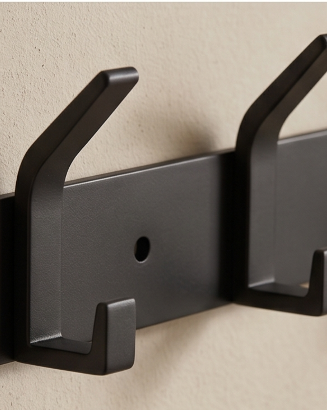 Black aluminum wall rack detail showing a hook, the mounting bar, the screw hole and the textured finish.