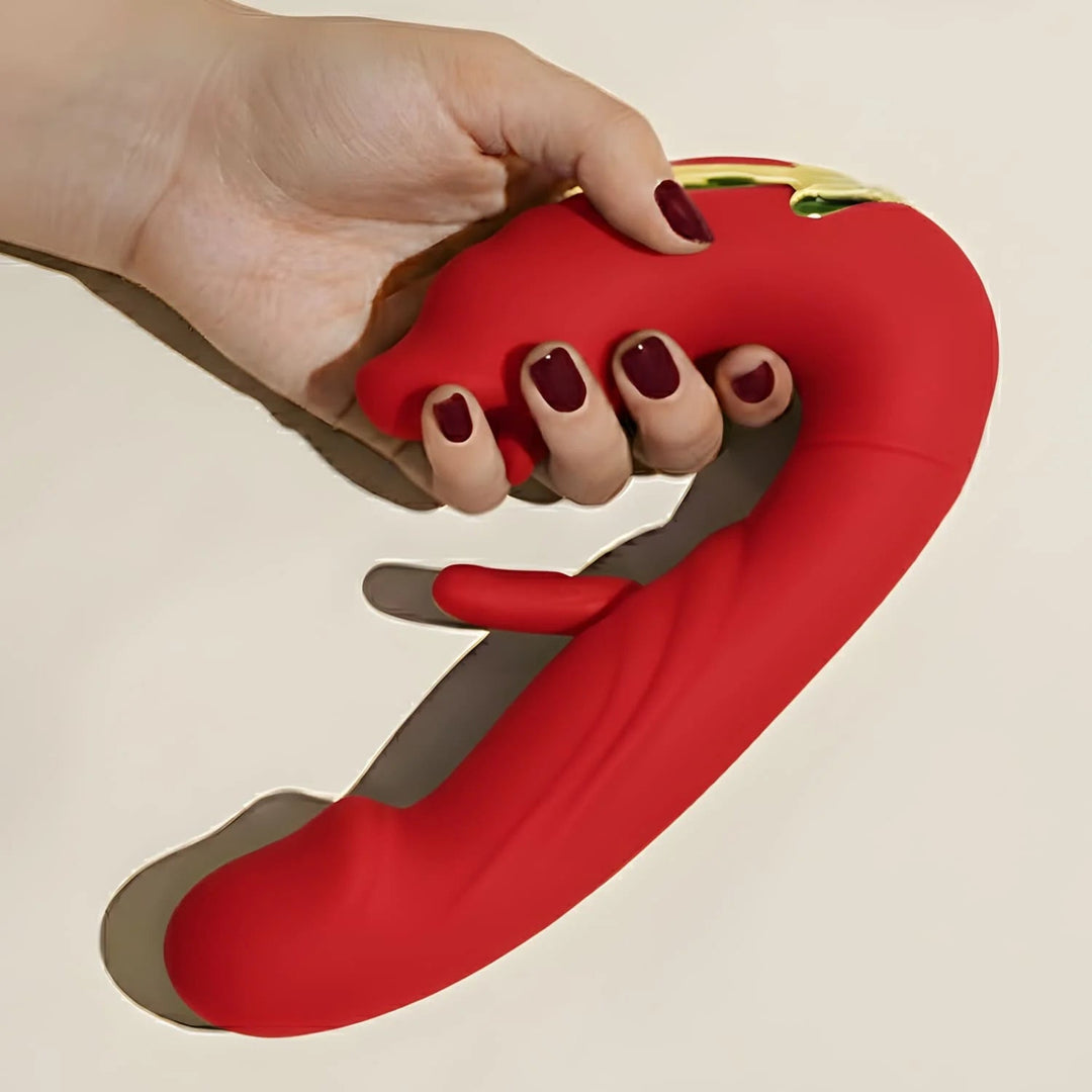 Hand with dark red nails gripping the handle of a red silicone dual-motor massager, showing its curved shape and small gold accent. 5