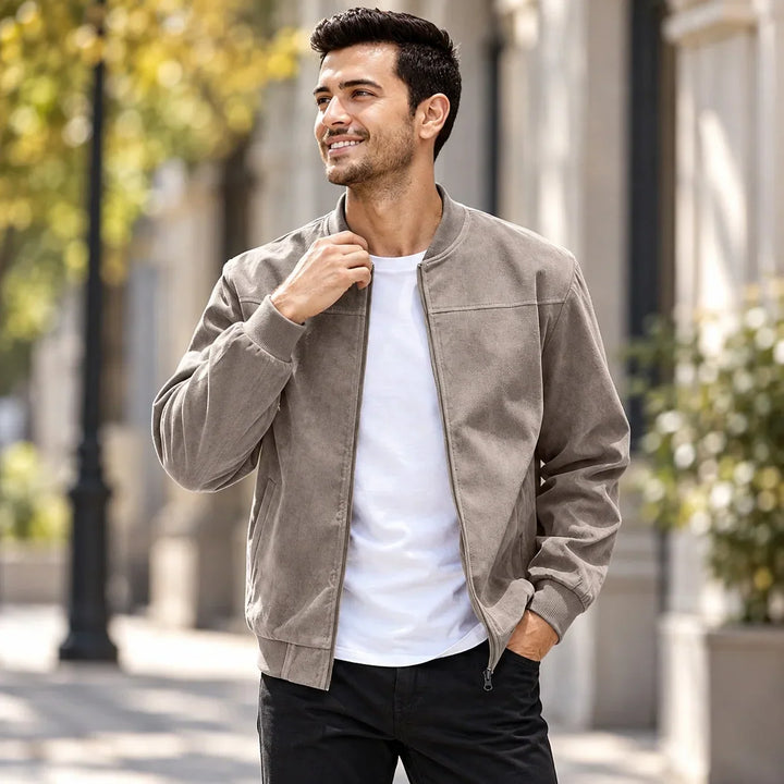Smiling man in a taupe zip-up jacket with ribbed trim, worn over a white tee outdoors 2