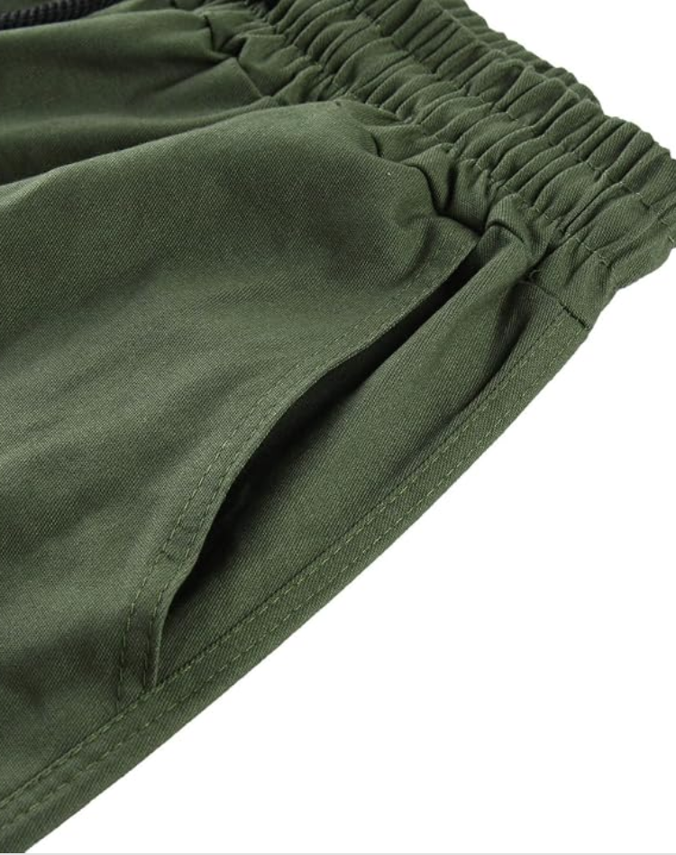 Close-up of the elastic waistband and slanted side pocket of olive green cargo pants. 13