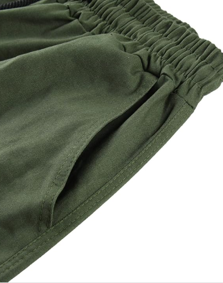 Close-up of the elastic waistband and slanted side pocket of olive green cargo pants. 13