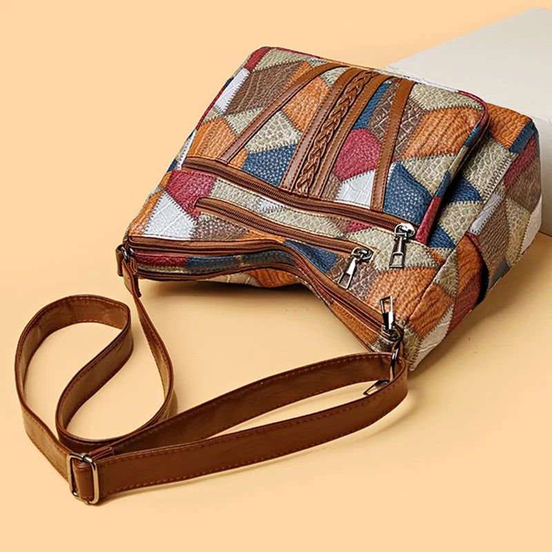 Bag lying on its side on a peach surface, showing the stacked top zippers and the adjustable brown strap with metal buckle. 7